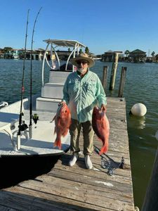 A fisherman holding two 18-inch fish in Port Isabel
