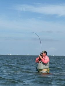 Wade fishing with bent rod indicating hooked fish in Corpus Christi TX waters