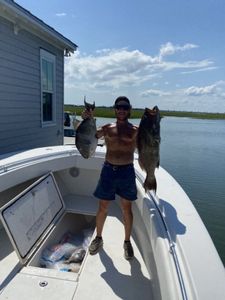 A person fishing with two large fish in Mount Pleasant