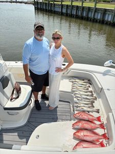 Successful red snapper fishing trip in Gulf Shores AL with large catch displayed on boat deck