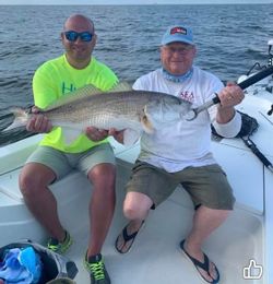 Two anglers holding a large redfish on a fishing boat in Gulf Shores AL