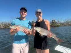 Two anglers displaying caught redfish on fishing boat in Cape Coral FL waters