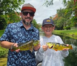 Two freshly caught peacock bass being displayed after successful fishing trip in Fort Lauderdale FL