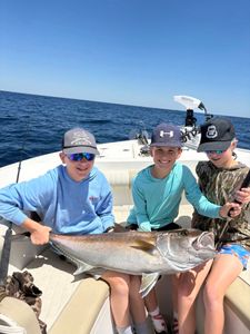 Three young anglers displaying a large Greater Amberjack caught while fishing in Niceville FL