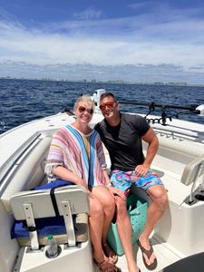 Two people relaxing on a fishing boat in Niceville FL waters with coastal buildings visible in the background