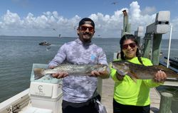 Two anglers displaying speckled trout and redfish caught in Corpus Christi TX