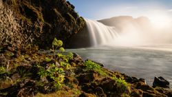 Waterfall cascading over moss-covered rocks into pool with mountains in background Florida City FL