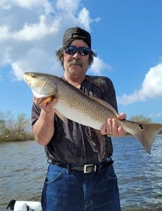 A fisherman holding a large redfish caught in Fort Myers