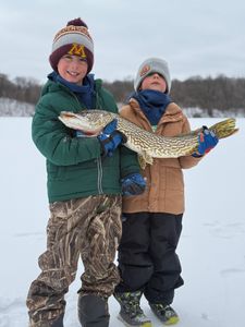 Two young anglers displaying a freshly caught Northern Pike during ice fishing in Stillwater MN