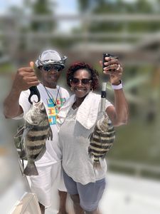 Two anglers holding black drum and sheepshead fish caught in Wilmington