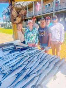 Large catch of fish displayed on cleaning table at Gulf Shores AL fishing dock with group posing behind