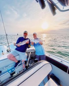 Successful fishing trip in Gulf Shores AL showing caught squeteague fish on boat deck at sunset