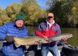 Two anglers displaying large Chinook salmon and Dolly Varden caught while fishing in Fruitport MI
