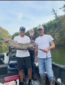 Three anglers on fishing boat displaying large Chinook salmon catch in Fruitport MI