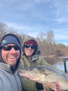 Two anglers holding a freshly caught walleye on a boat in Fruitport MI