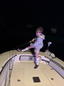 Night fishing from boat deck in Chesapeake FL with fishing rod extended over dark water