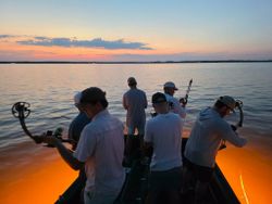 Fishing boat at sunset in Orange Beach AL with anglers preparing their gear on calm water