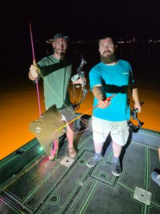 Bowfishing setup on boat deck at night in Orange Beach AL with illuminated water