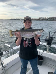 A fly fisherman catches a large rainbow trout in NY.