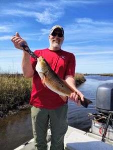 Angler in red shirt with his trophy Redfish