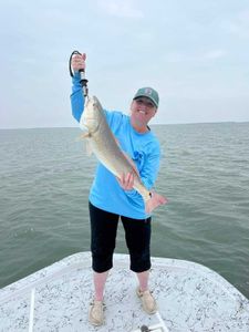 A person fishing in TX holding a 22-inch fish