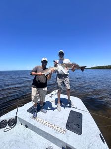 Two anglers displaying caught redfish on fishing boat in Punta Gorda FL waters