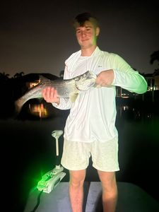Angler holding caught tarpon on fishing boat at night in Punta Gorda FL