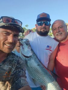 Three anglers displaying a large tarpon catch in Punta Gorda FL