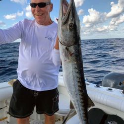 A fisherman holding a large king mackerel fish caught in West Bay