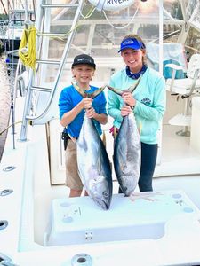Two anglers reeling in big fish from a boat in New Jersey