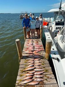 Large fishing catch displayed on dock at Holmes Beach FL with fishing boat