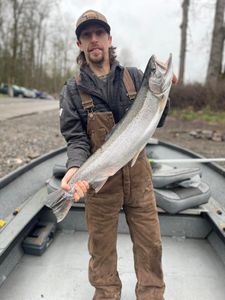 A fisherman proudly holding a large rainbow trout in Toledo
