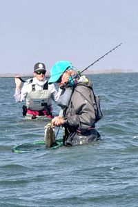Anglers wade fishing in shallow water near Corpus Christi TX with fishing rod and net