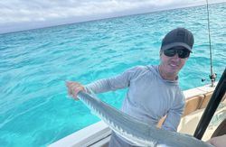 Angler holding barracuda catch on fishing boat in crystal clear waters off Islamorada FL