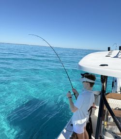 Fishing from boat in clear turquoise waters off Islamorada FL with bent fishing rod