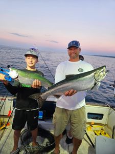 Two anglers displaying fresh caught Chinook salmon on fishing boat in Port Washington WI