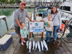 Family fishing charter displaying fresh caught Coho and Chinook salmon on dock in Port Washington WI