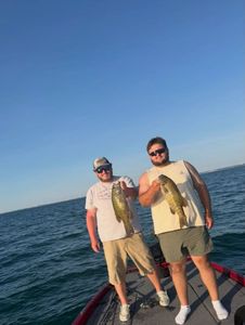 Two anglers display caught smallmouth bass on fishing boat in North Tonawanda NY waters