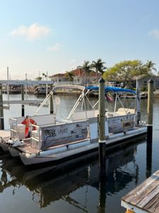 Charter fishing boat Liberty docked at marina in New Port Richey FL with blue canopy and outriggers