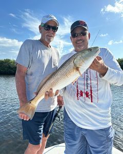 Two anglers displaying a large redfish caught while fishing in New Port Richey FL