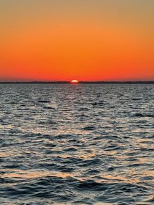 Sunset over calm waters in New Port Richey Florida with orange sky and gentle waves
