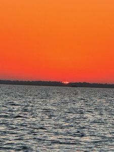 Sunset over calm waters near New Port Richey FL with orange sky and distant shoreline