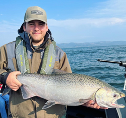 Photograph of a fisherman holding a large rainbow trout in Portland, Oregon