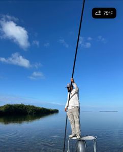 Angler standing on boat bow with fishing pole in shallow waters near mangroves in Islamorada FL
