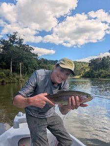 Smiling person holding a rainbow trout while fishing in Missouri