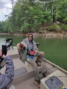 Angler holding caught crappie on fishing boat in Gainesville GA lake with wooded shoreline