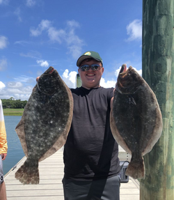 Photograph of a fisherman holding two large Pacific Halibut and Southern Flounder in South Carolina