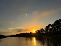 Sunset over calm water with treeline silhouette in North Myrtle Beach SC fishing location