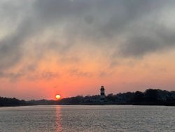 Sunset view over water with lighthouse and treeline in North Myrtle Beach SC
