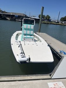White fishing boat with turquoise leaning post docked at marina in Port Aransas TX